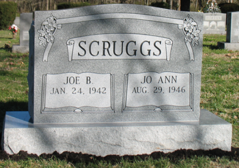 A grey granite headstone in a cemetery with 