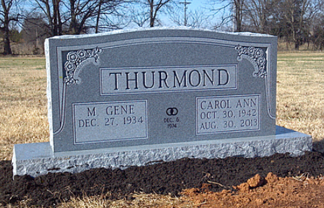A granite cemetery headstone for the Thurmond family, featuring the names and dates for M. Gene and Carol Ann Thurmond.