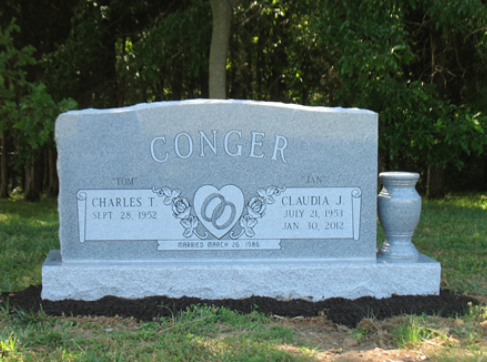 A gray granite headstone for Charles T. and Claudae J. Conger, inscribed with dates and a central heart with rings motif.