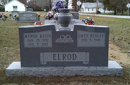Gray granite double headstone for Myron Keith and Gwen Henley Elrod, with marriage date and floral arrangements in a yard.