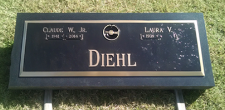 A black rectangular granite gravestone with a bronze plaque labeled 