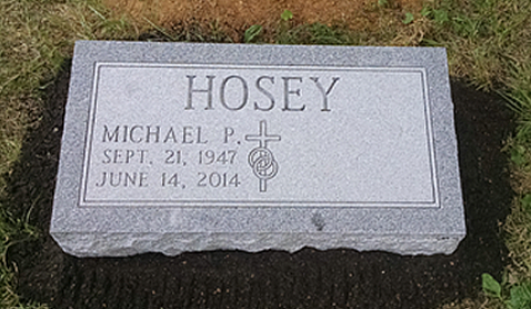 A gray granite grave marker for Michael P. Hosey, inscribed with his birth and death dates and a cross symbol.