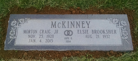 A grey stone grave marker for the McKinney family, dated June 8, 1954, set in the grass.