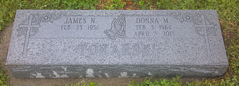 A flat gray granite grave marker for James N. and Donna M. in a grassy setting.