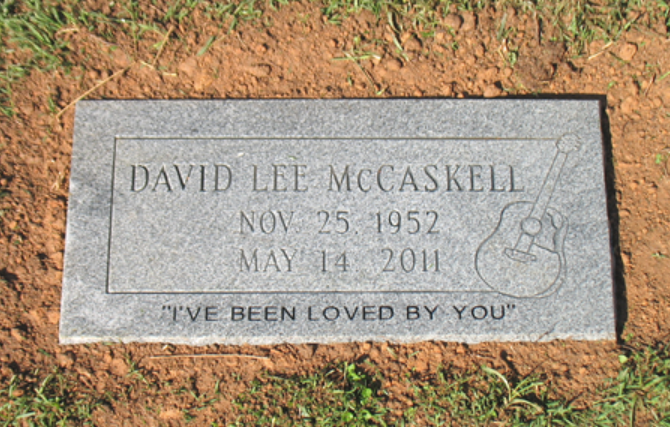 A gray granite gravestone for David Lee McCaskell (Nov 25, 1952 – May 14, 2011) with a guitar etching and a loving epitaph.