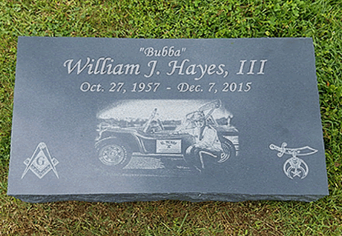 Dark gray granite headstone for William J. Hayes, III, featuring a car engraving and Masonic and Shriners symbols.