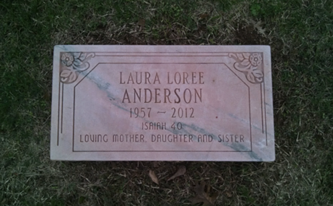 A rectangular pink granite grave marker for Laura Loree Anderson, inscribed with her name, years 1957–2012, and epitaph.