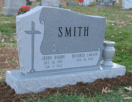 Gray granite headstone for the Smith family, featuring a cross and Masonic emblem, set in a cemetery.