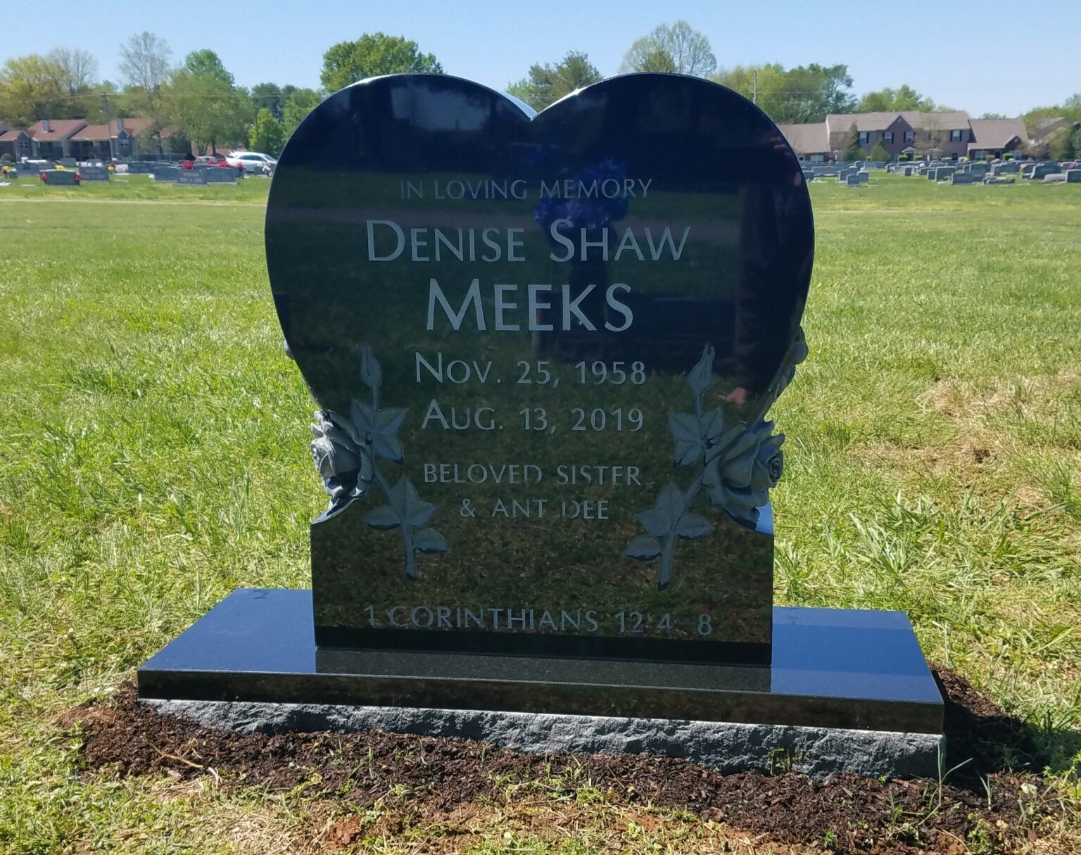 A heart-shaped black granite gravestone for Denise Shaw Meeks, set in a grassy cemetery.