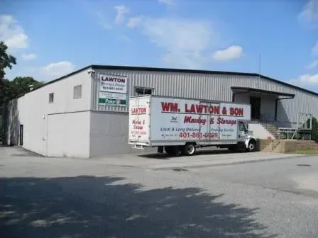 A moving truck from Wm. Lawton & Son parked outside their storage warehouse on a sunny day.