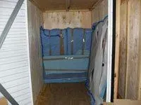 Blue padded furniture covers inside a wooden moving container, likely preparing for transport.