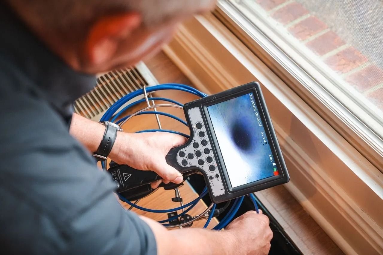 Man using a camera scope, looking at a screen near a window.