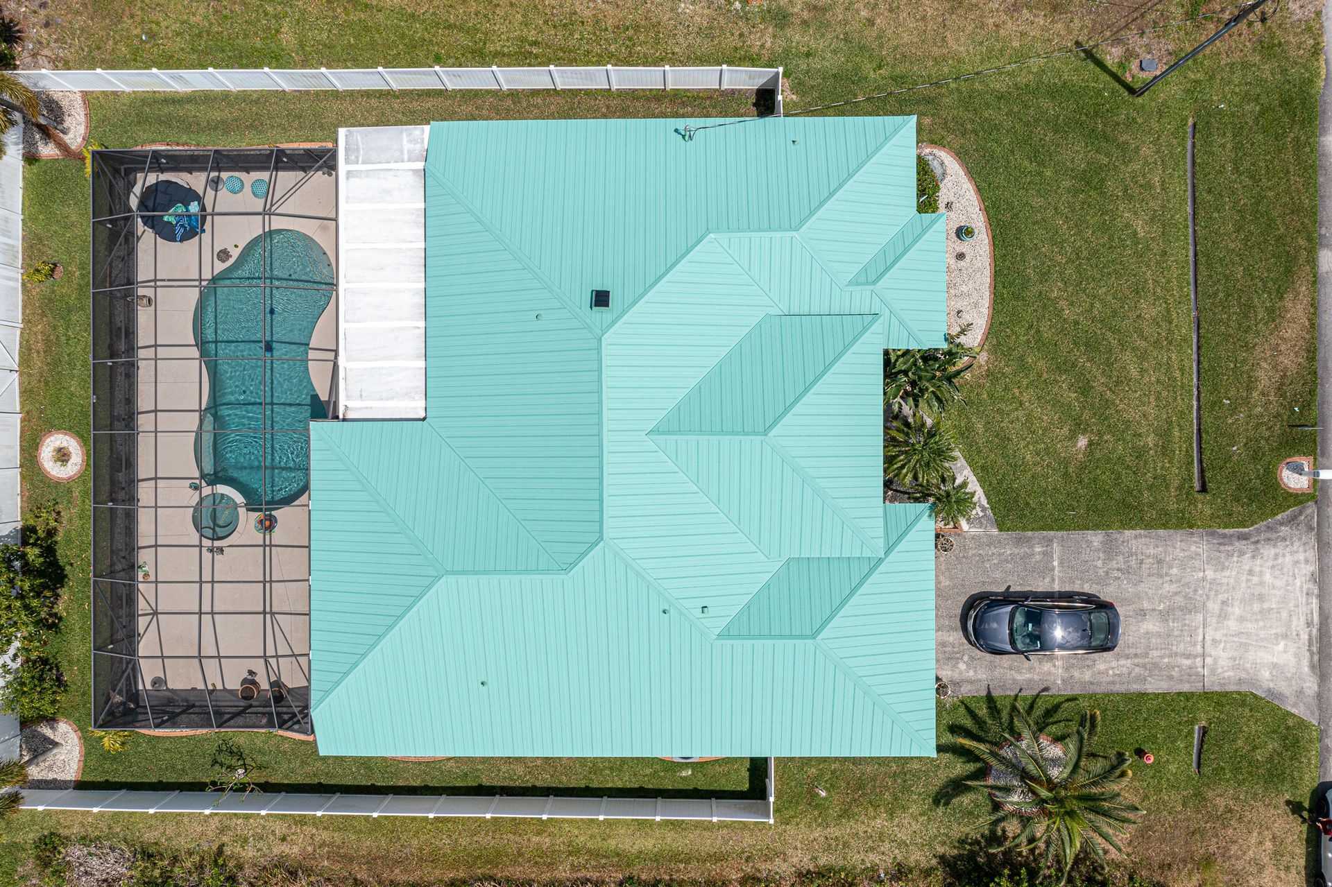 An aerial view of a house with a green roof and a pool.