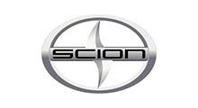Scion car logo: Silver, circular emblem with the brand name in a box and a cross-shaped design.