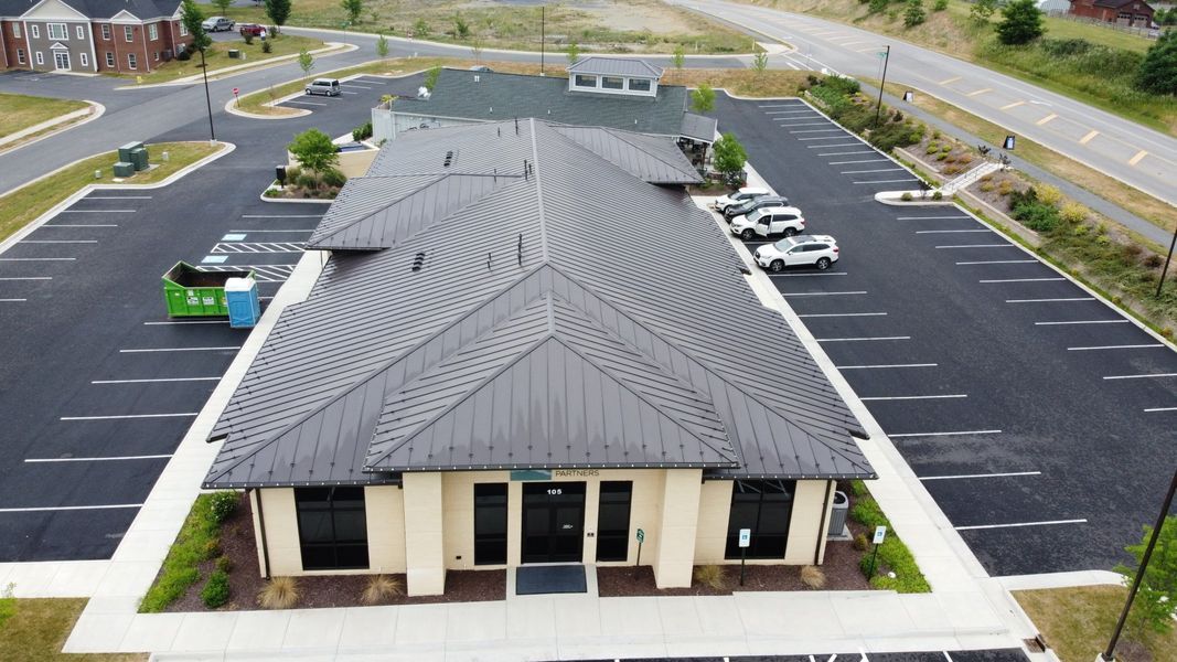 Building with a patterned dark roof and surrounding parking lot.