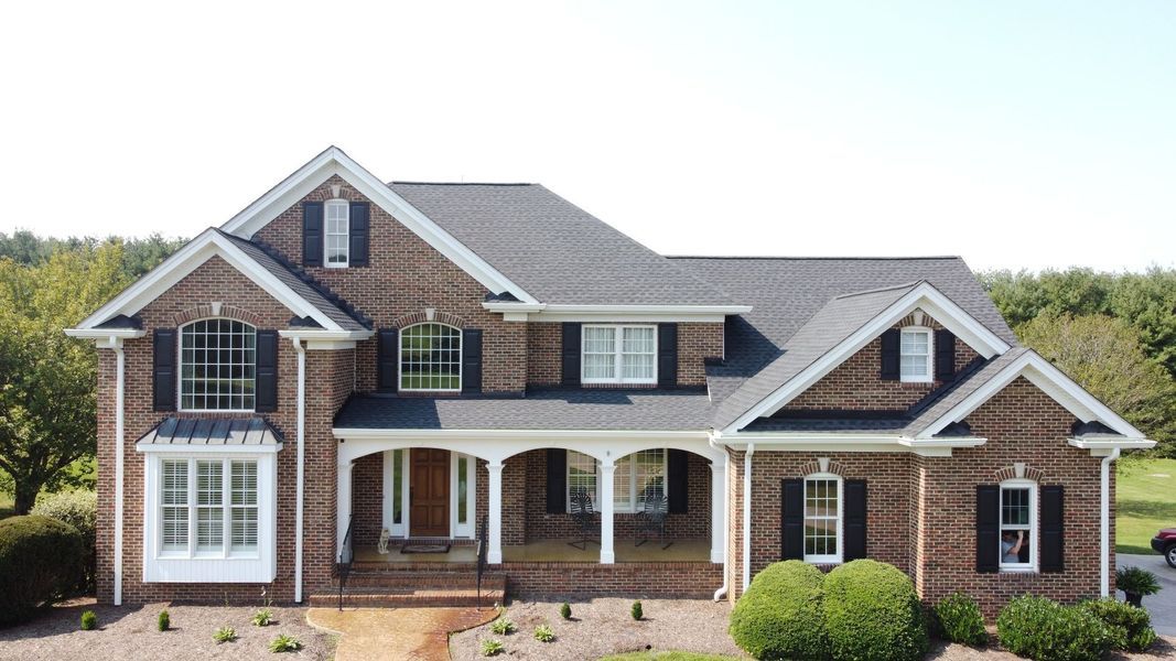 Brick two-story house with black shutters and a covered porch.