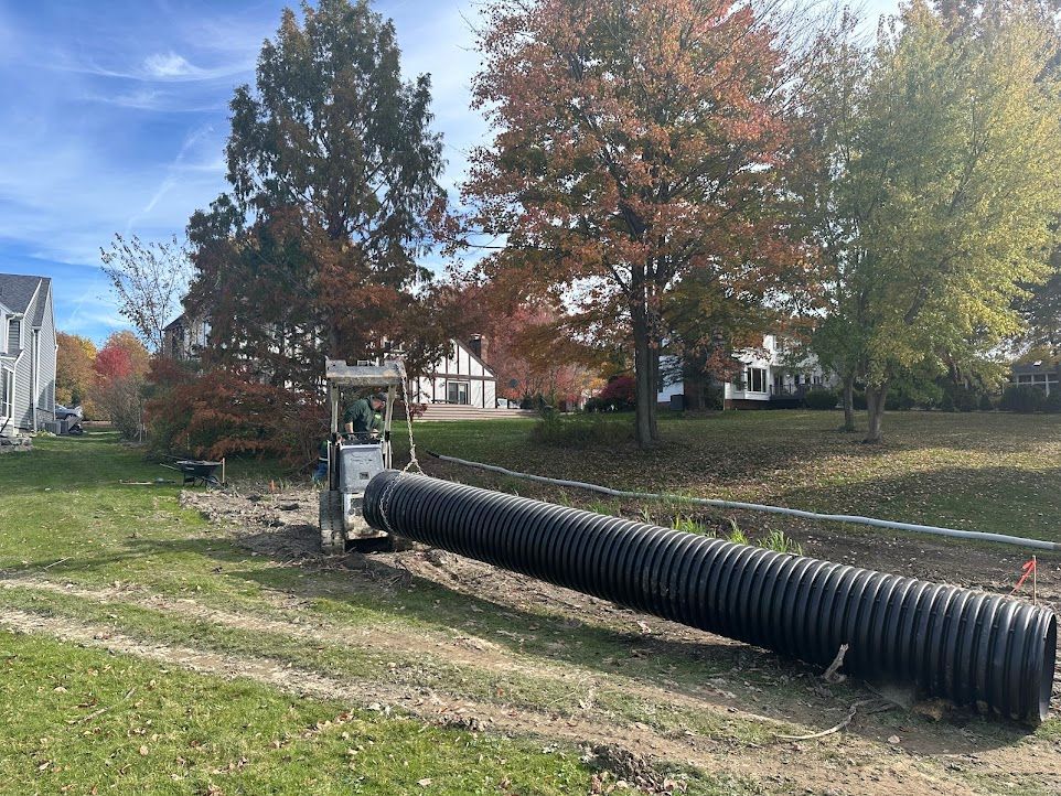 A large black pipe is sitting in the middle of a grassy field.