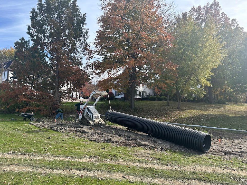 A large black pipe is laying on the ground in a field.