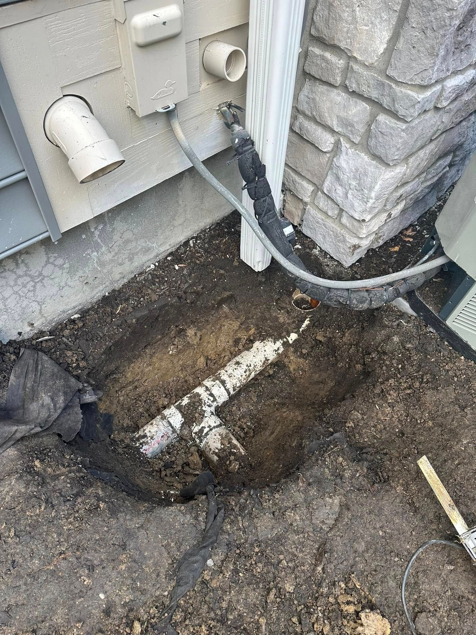 A person is digging a hole in the ground to fix a pipe.