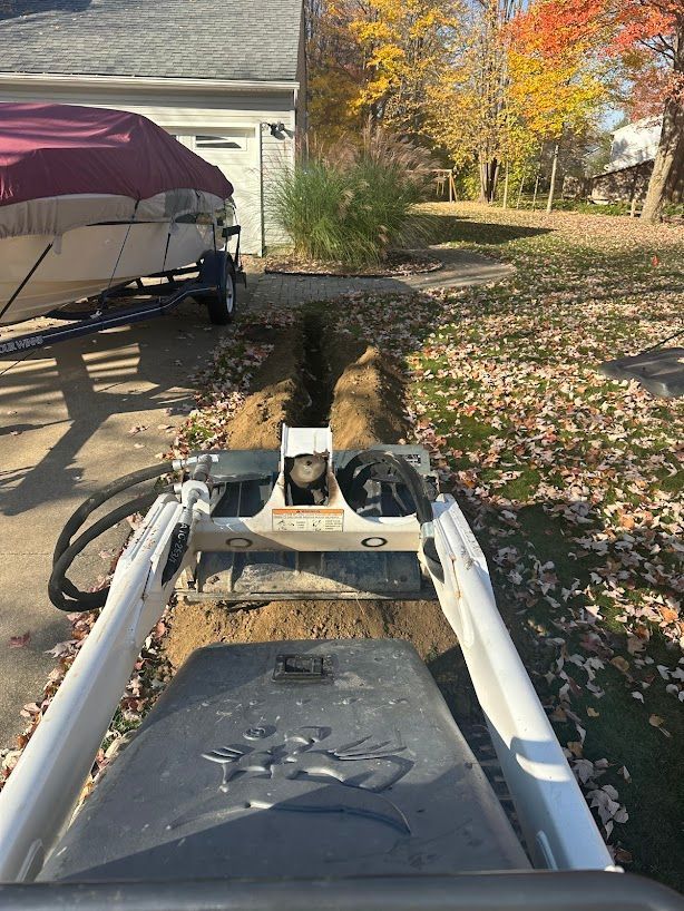 A tractor is digging a hole in the ground in front of a house.