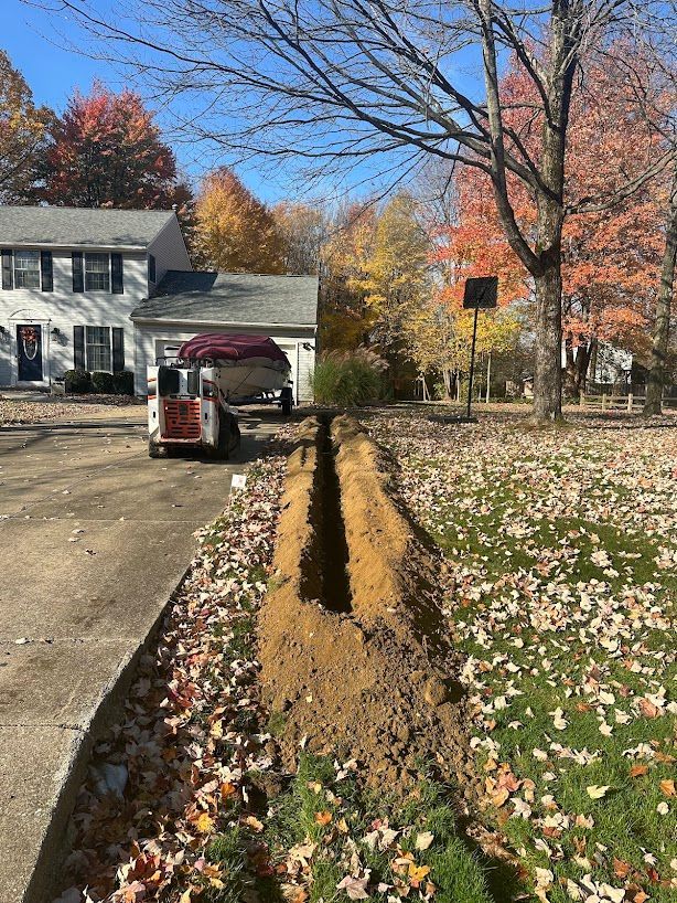 A machine is digging a hole in the ground in front of a house.