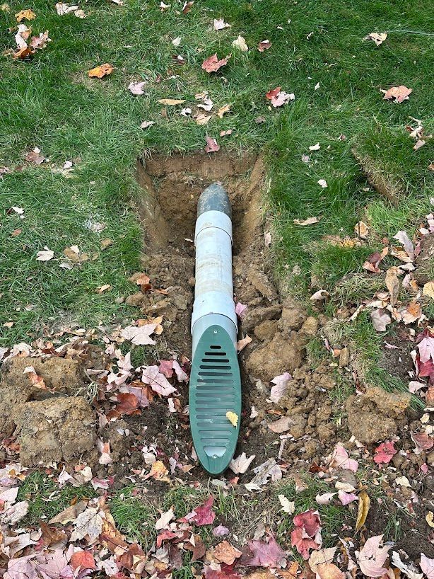 A green pipe is sitting in the middle of a hole in the ground.