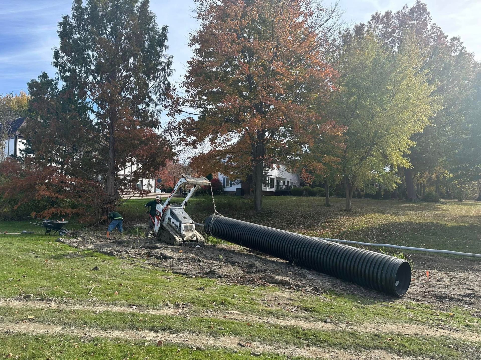 A large black pipe is laying on the ground in a field.