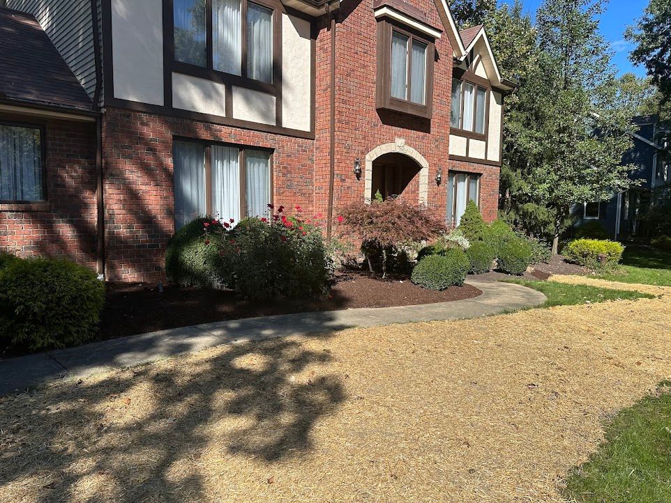 A large brick house with a gravel driveway in front of it.