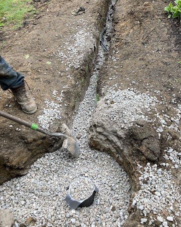 A person is digging a trench in the ground with a shovel.