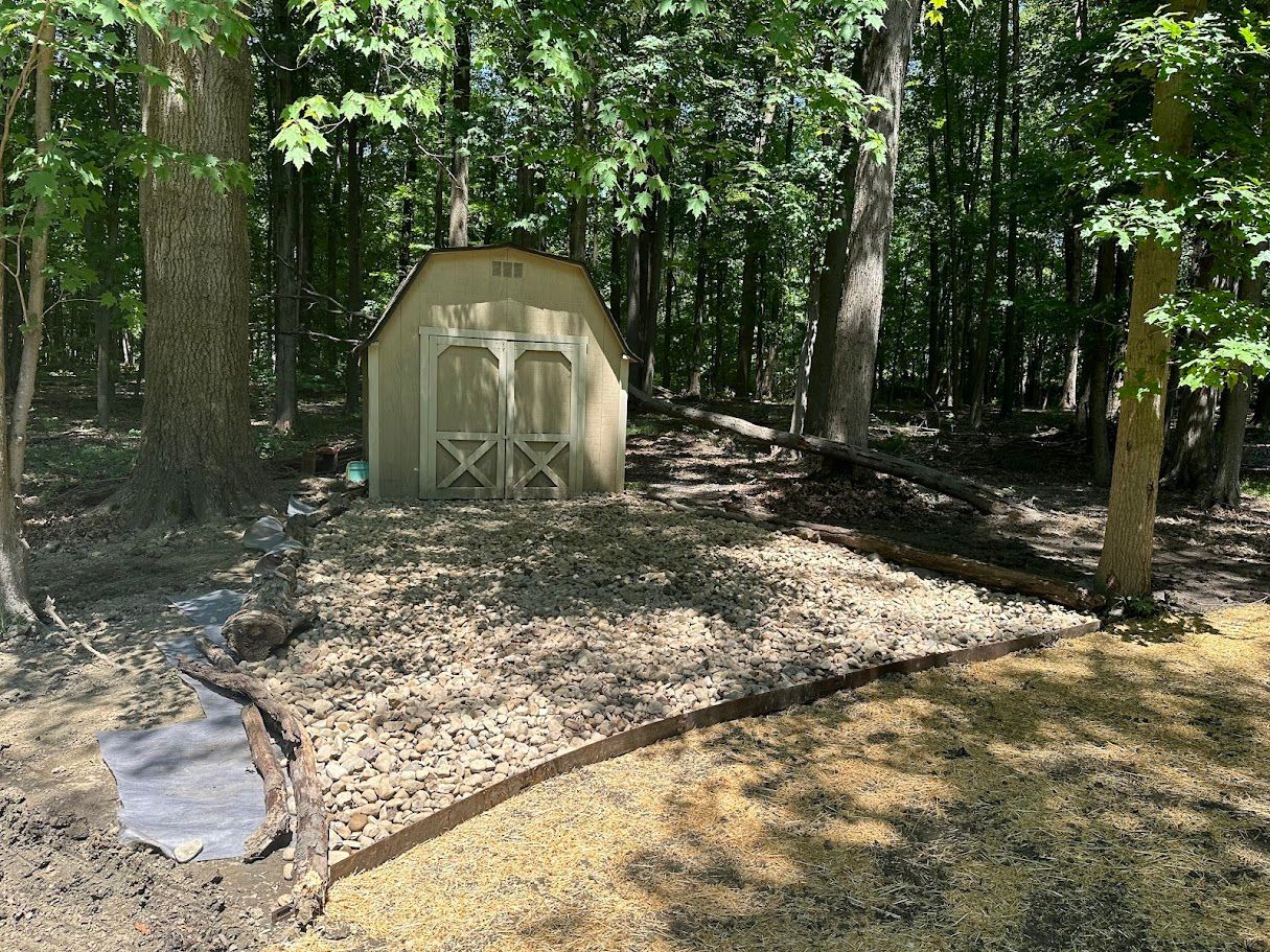 A small barn is sitting in the middle of a forest.