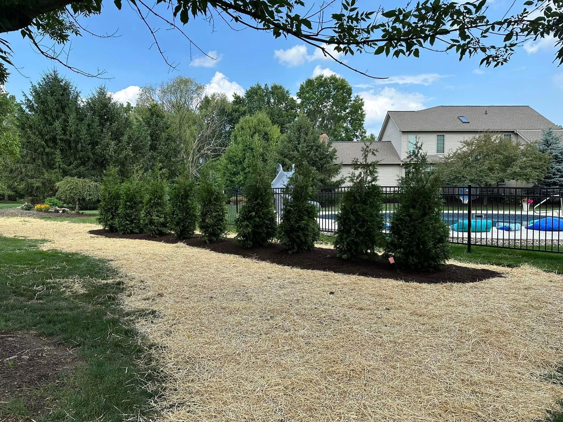 A gravel driveway leading to a house with a pool in the background.