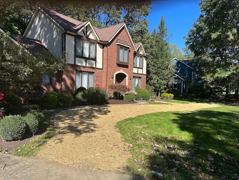 A large brick house with a gravel driveway in front of it.