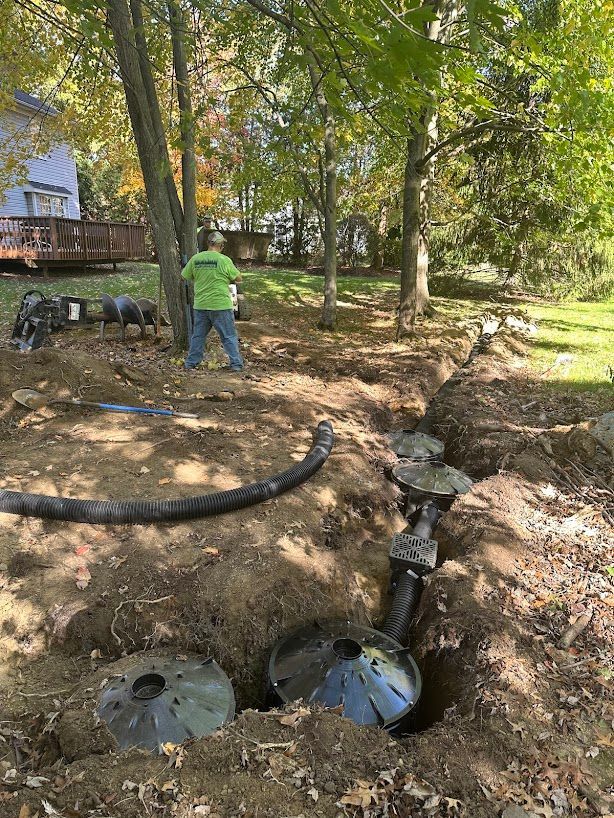 A man is standing in the dirt next to a septic tank.