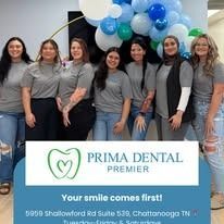Group of smiling women in front of a dental office sign and balloon arch.