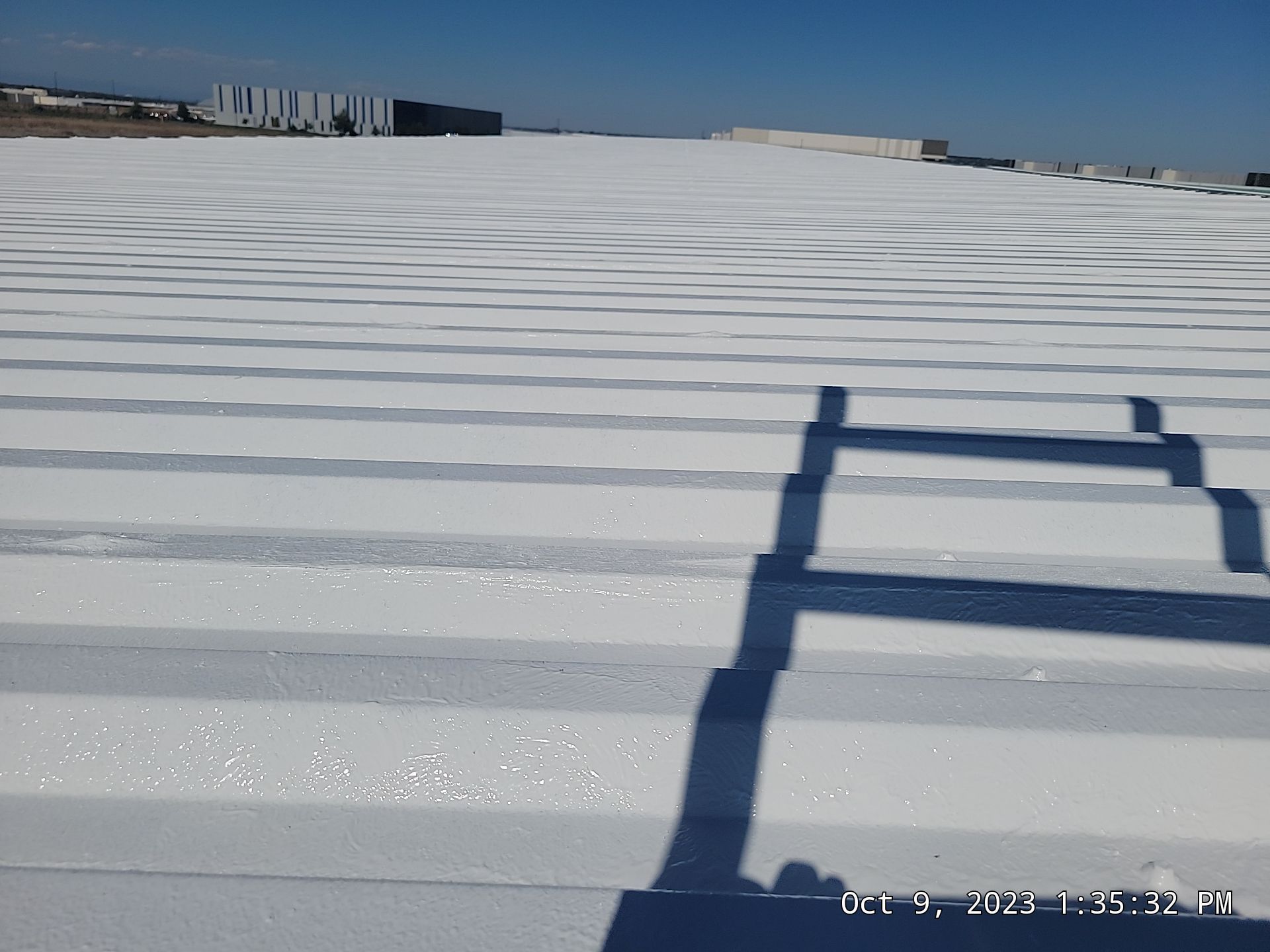 A shadow of a ladder is cast on a white roof