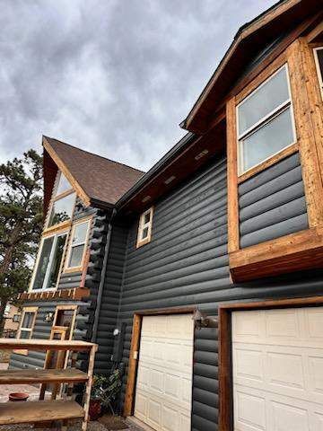 A large log cabin with a garage and a lot of windows.