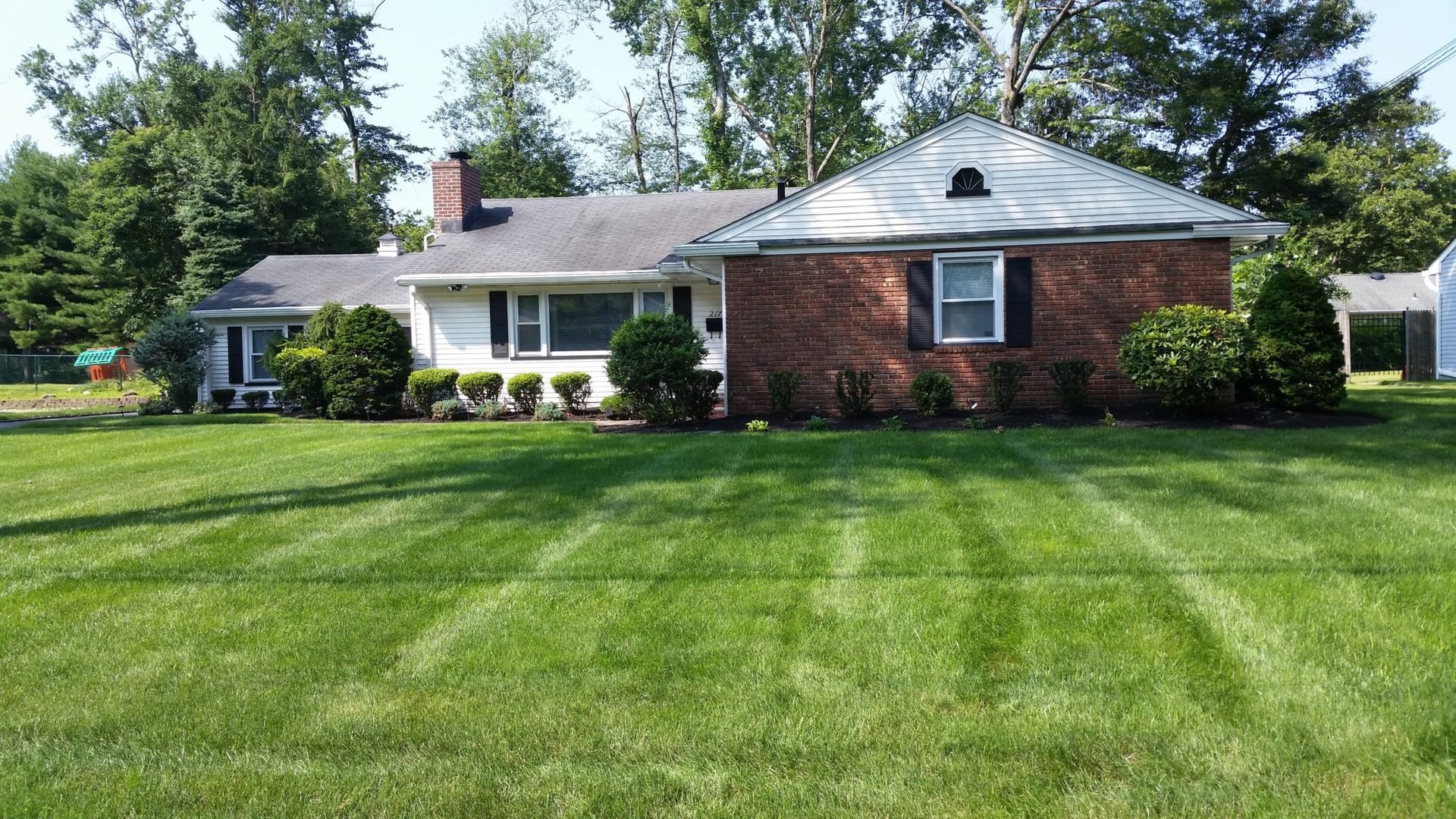 A brick house with a lush green lawn in front of it.