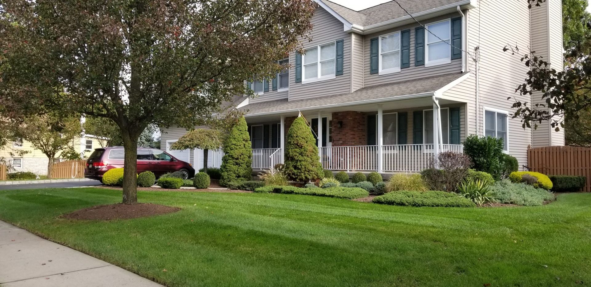 A house with a lush green lawn and a car parked in front of it.
