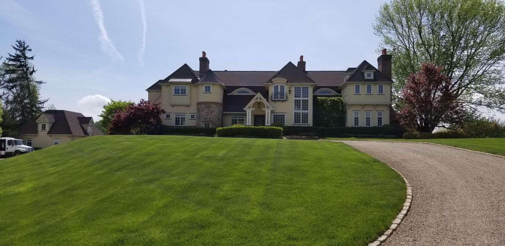 A large house with a gravel driveway leading to it.