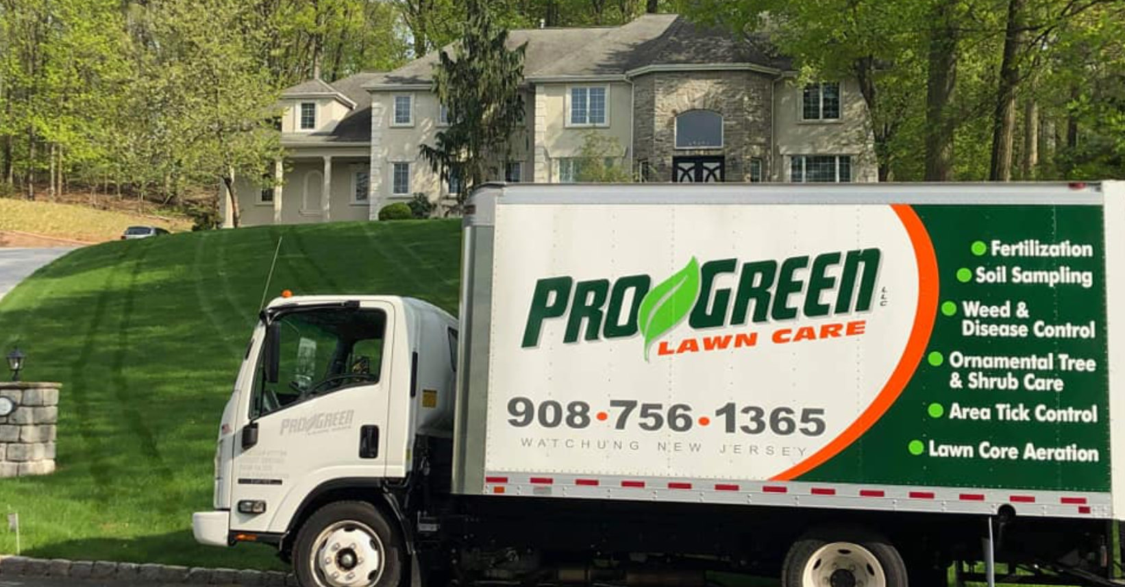 A pro green lawn care truck is parked in front of a house.