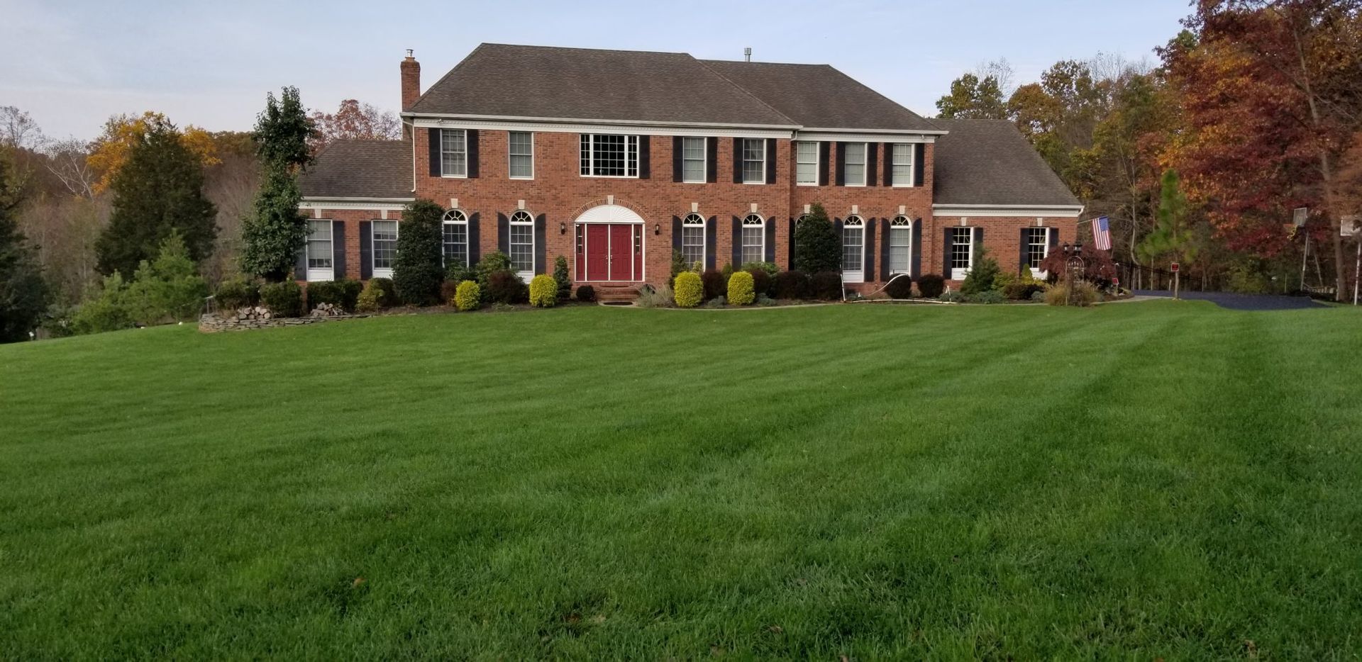 A large brick house with a lush green lawn in front of it