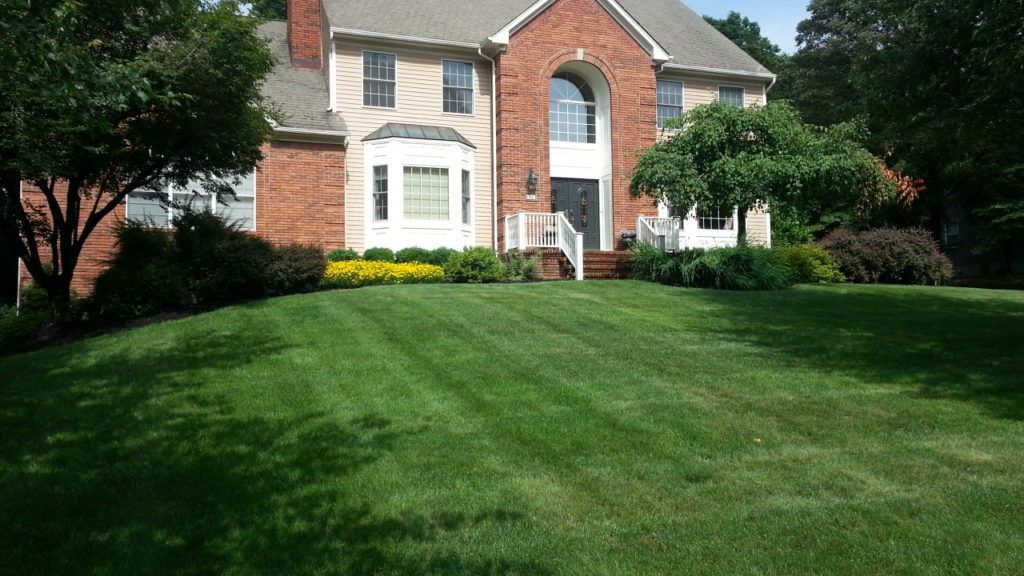 A large brick house with a lush green lawn in front of it.