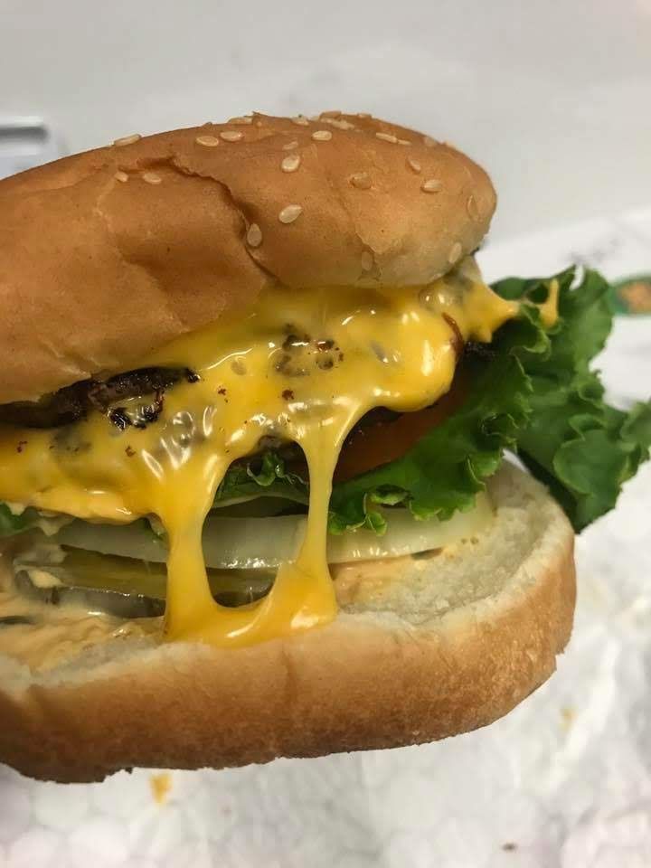 A close-up of a cheeseburger with lettuce and pickles