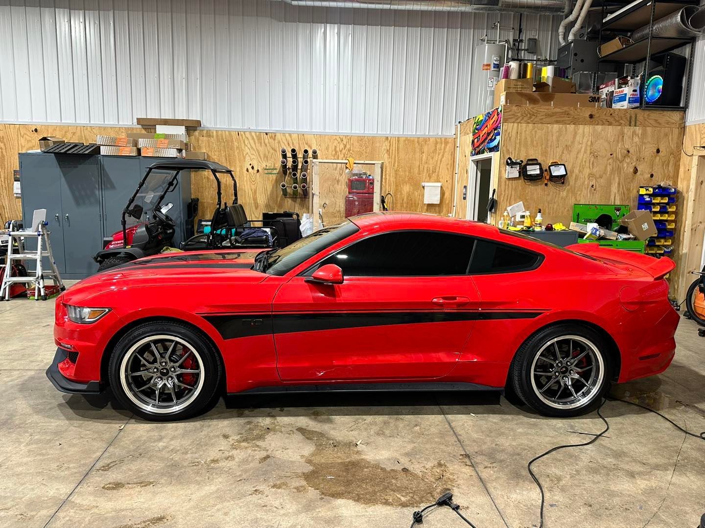 A red mustang is parked in a garage.