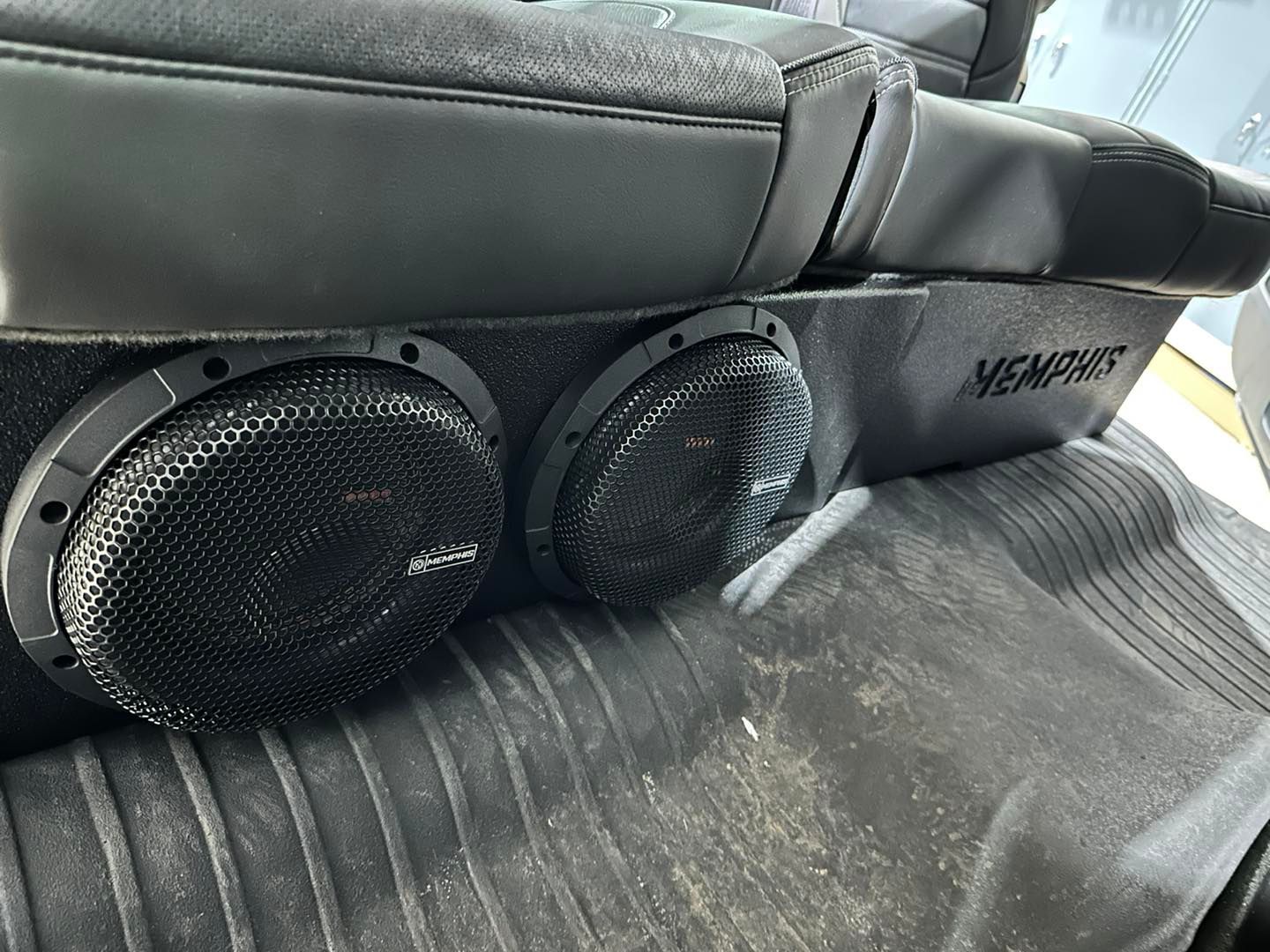 There are two speakers in the back of a car.