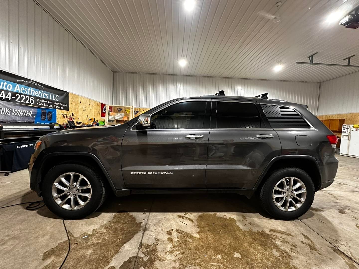 A gray jeep grand cherokee is parked in a garage.
