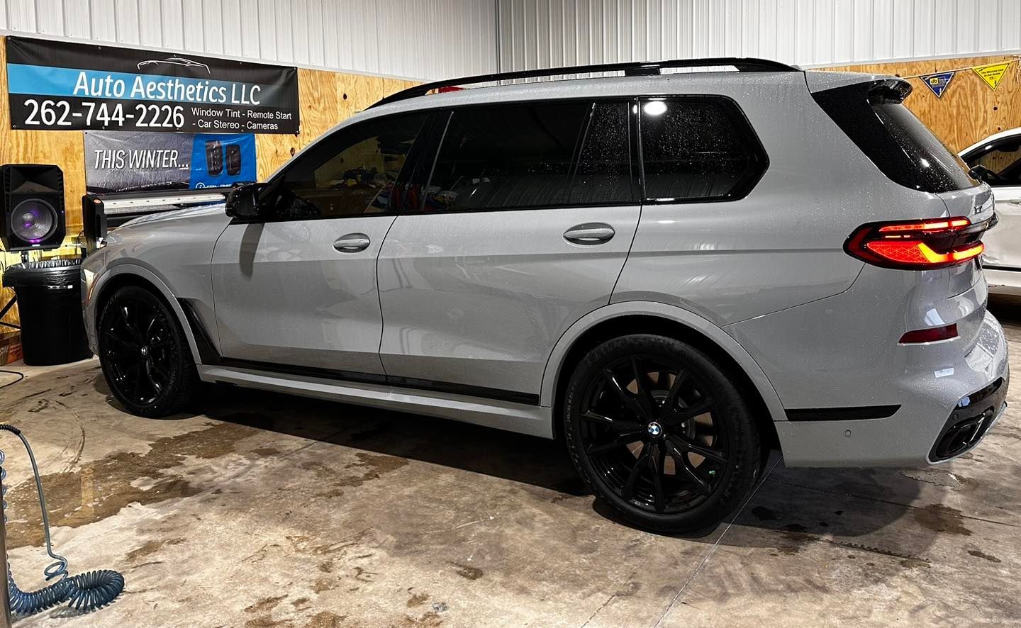 A gray bmw x7 is parked in a garage.