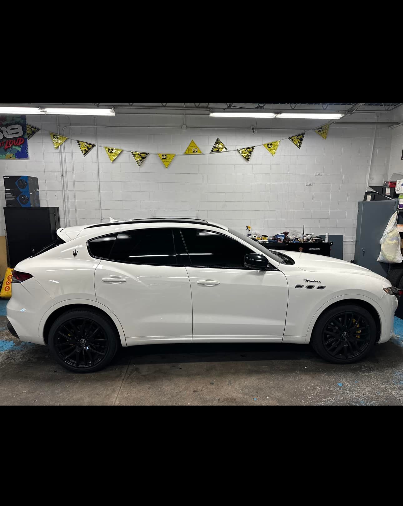 A white car is parked in a garage with black wheels.