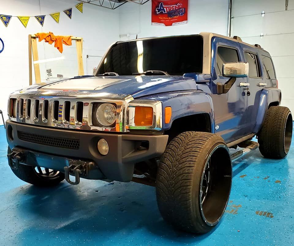 A blue hummer is parked on a blue floor in a garage.