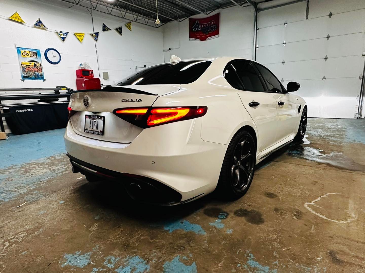 A white car is parked in a garage next to a garage door.